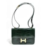 A dark green crocodile skin shoulder/handbag with a gold tone 'H' fastener and hardware, in the