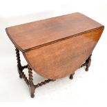 A 1920s/30s oak drop leaf gateleg dining table raised on barley twist supports, width 106cm,