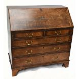 A late George III oak and mahogany crossbanded North Country bureau with carved detail to fall