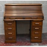 An early 20th century oak roll top desk, the interior enclosing a selection of pigeon holes and