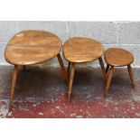 ERCOL; a nest of three graduated 'Pebble' coffee tables, raised on turned column supports.Additional