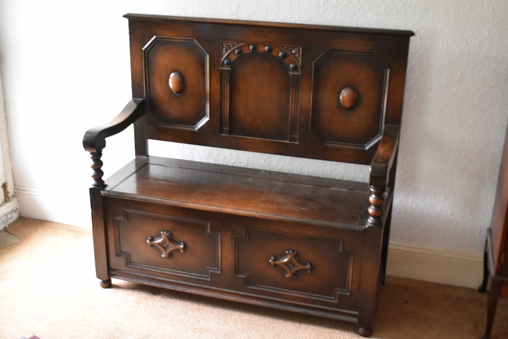 A 1920s oak settle, with panelled back and box seat, on turned feet, height 113cm, width 121cm,