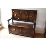 A 1920s oak settle, with panelled back and box seat, on turned feet, height 113cm, width 121cm,