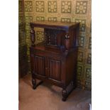 A 1940s carved and stained oak court cupboard, with arched panelled door above two linenfold