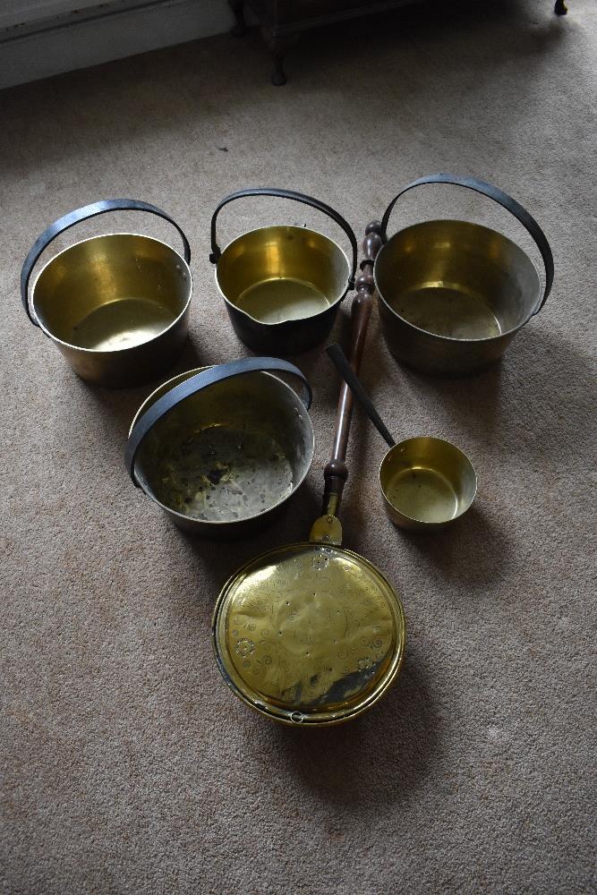 Four brass and cast iron preserving pans, the largest diameter 32.5cm, also a smaller brass saucepan