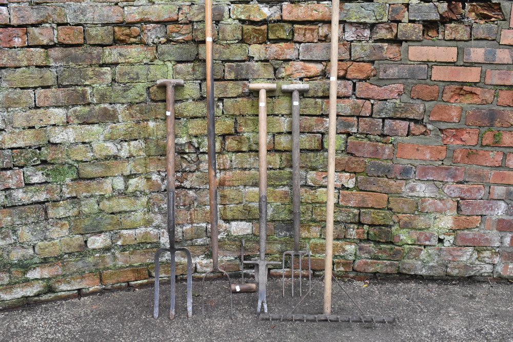 A collection of five vintage, agricultural and garden tools, including a pikel, garden rake, a broad