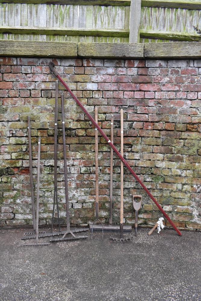 A collection of nine vintage agricultural and garden tools, including a long armed lopper, six