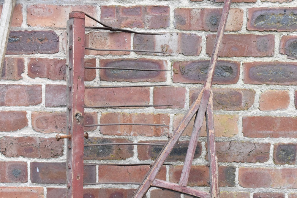 A vintage red painted wood and iron hay rake, two scythes, two potato forks, a fork and a fork head. - Image 7 of 8