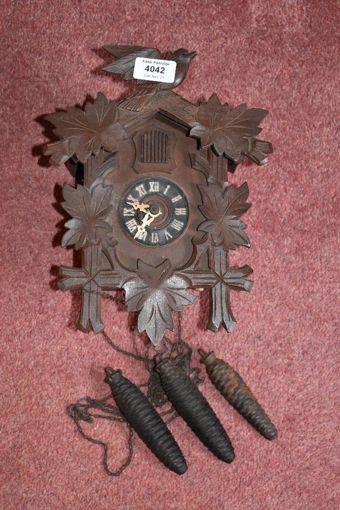 A Black Forest type cuckoo clock, with two cast iron acorn shaped weights, height 29cm.