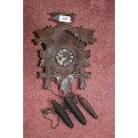 A Black Forest type cuckoo clock, with two cast iron acorn shaped weights, height 29cm.