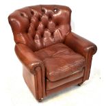 A brown leather button back armchair, on turned feet, height 94cm, width 90cm.