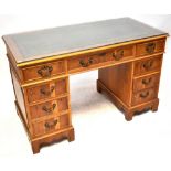 A modern reproduction pedestal desk, with inset green leather top and glass top,