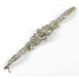 A white metal and diamond set articulated bracelet the centre in the form of a flower flanked by