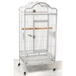 A grey painted metal parrot cage with arched top and single door, on legs with castors,