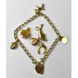 A 9ct gold charm bracelet with three charms and heart-shaped clasp,