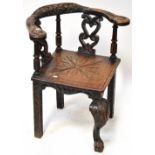 An early 18th century oak corner chair in the Flemish style, curved top and foliate back rail,