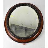 A wall-mounted oval bevel edged mirror within oval walnut-effect frame, with raised piecrust border,