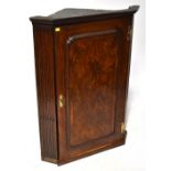 An early 19th century mahogany wall-hanging corner cabinet with shaped fronted internal shelves,