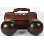 A cased pair of lignum vitae bowls with ivory inset tokens, in a leather bowl bag.