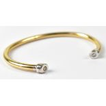 A 9ct yellow and white gold torc-style bracelet, with diamond to each white gold end piece,