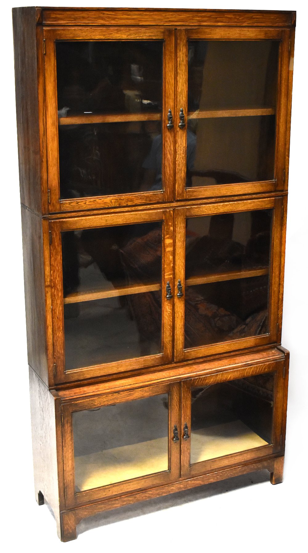 A 1930s oak three-tier bookcase, each tier with a pair of glazed cupboard doors,