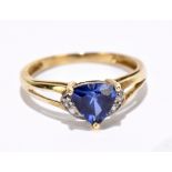 A yellow metal dress ring set with central pale blue Trilliant cut stone within illusion setting,