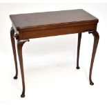 An Edwardian mahogany foldover games table, the folding top enclosing four copper dishes and baize