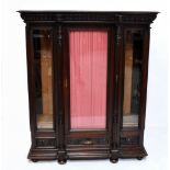 A 19th century French oak display cabinet, the carved cornice decorated with a male and female mask,