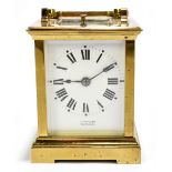 A circa 1900 brass repeating carriage clock with swing loop handle above white enamel dial set