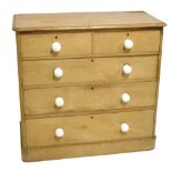 An old pine chest of two short over three long drawers, with white ceramic handles, raised on plinth