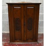 A 20th century carved oak hanging corner cabinet with two panelled doors enclosing five shelves,