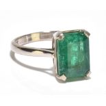 An 18ct white gold and emerald solitaire ring, the emerald cut stone weighing approx 3ct in four