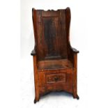 An early 19th century stained wing back pine lambing chair with drawer to base and raised on