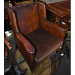 An early 20th century child's wing back armchair with leatherette material and studded edge,