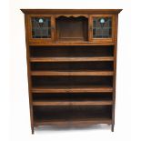 An early 20th century oak bookcase, the moulded dentil cornice above two leaded glazed cupboard