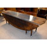 A large oak wake table in the George II style, the plank top with oval flaps raised on turned