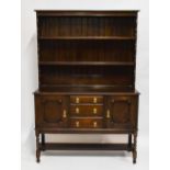 A 1920s oak dresser, the upper section with two shelves above three central drawers and two cupboard