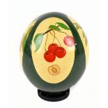 An ostrich egg painted with four oval panels of fruits on a dark green ground, length 14cm.