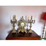 Brass clock garniture with a pair of ornate candelabra. Includes 2 keys and pendulum. Condition.