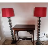 A pair of contemporary floor standing standard lamps. cast metal black stems with dark red shades.
