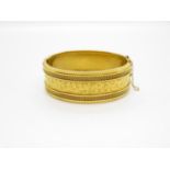 Early solid gold 9ct fully hallmarked bangle with safety chain on an embossed and filigree front