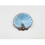 Silver and enamel brooch showing a pixie sitting in a shell