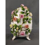 Porzellan-Ei, dekoriert mit vollplastischen Rosen und applizierten Blättern, auf drei partiell verg