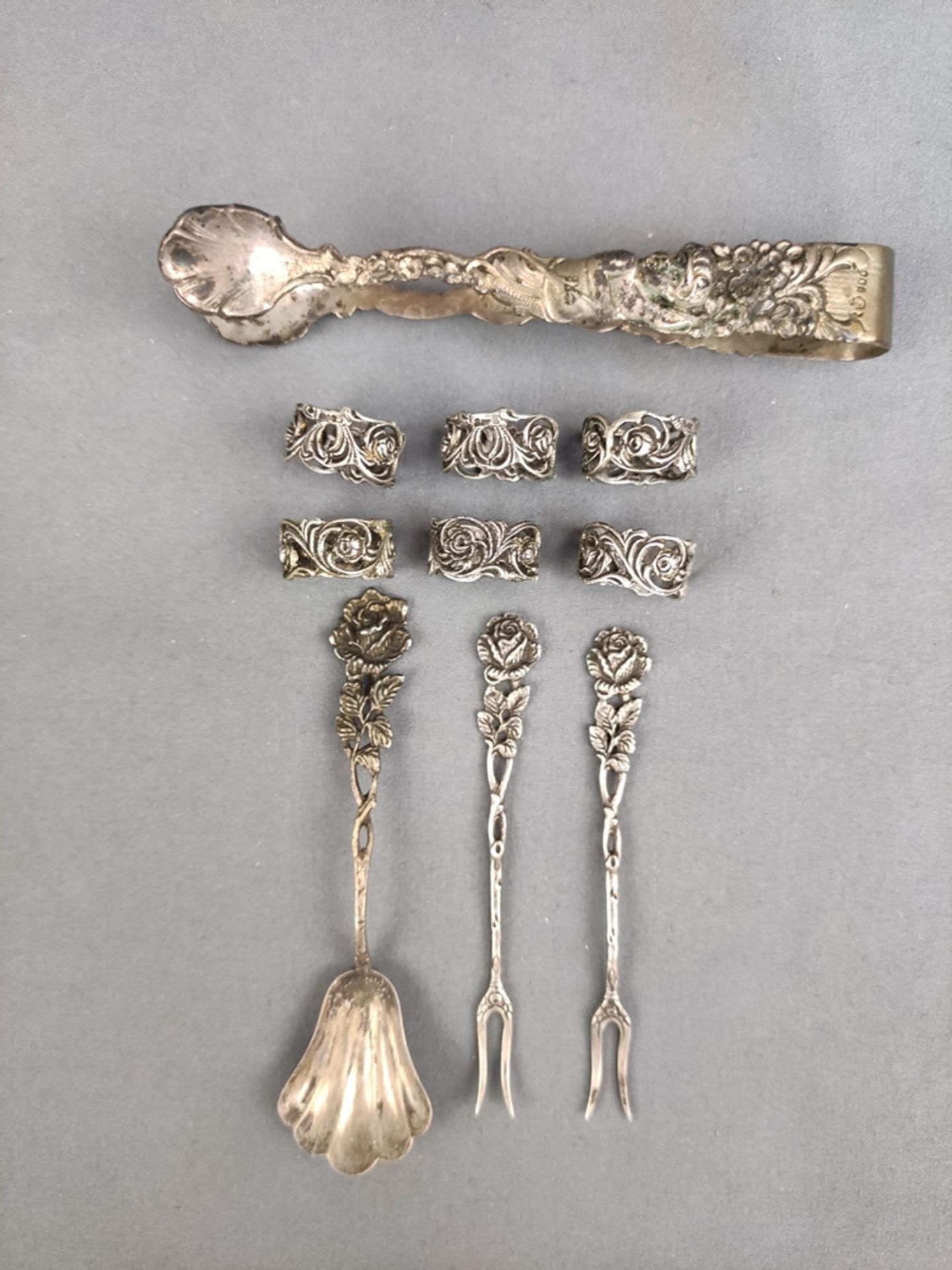 Silver lot, 6 napkin rings and four 4 other silver pieces (sugar tongs, two skewer forks and a sugar