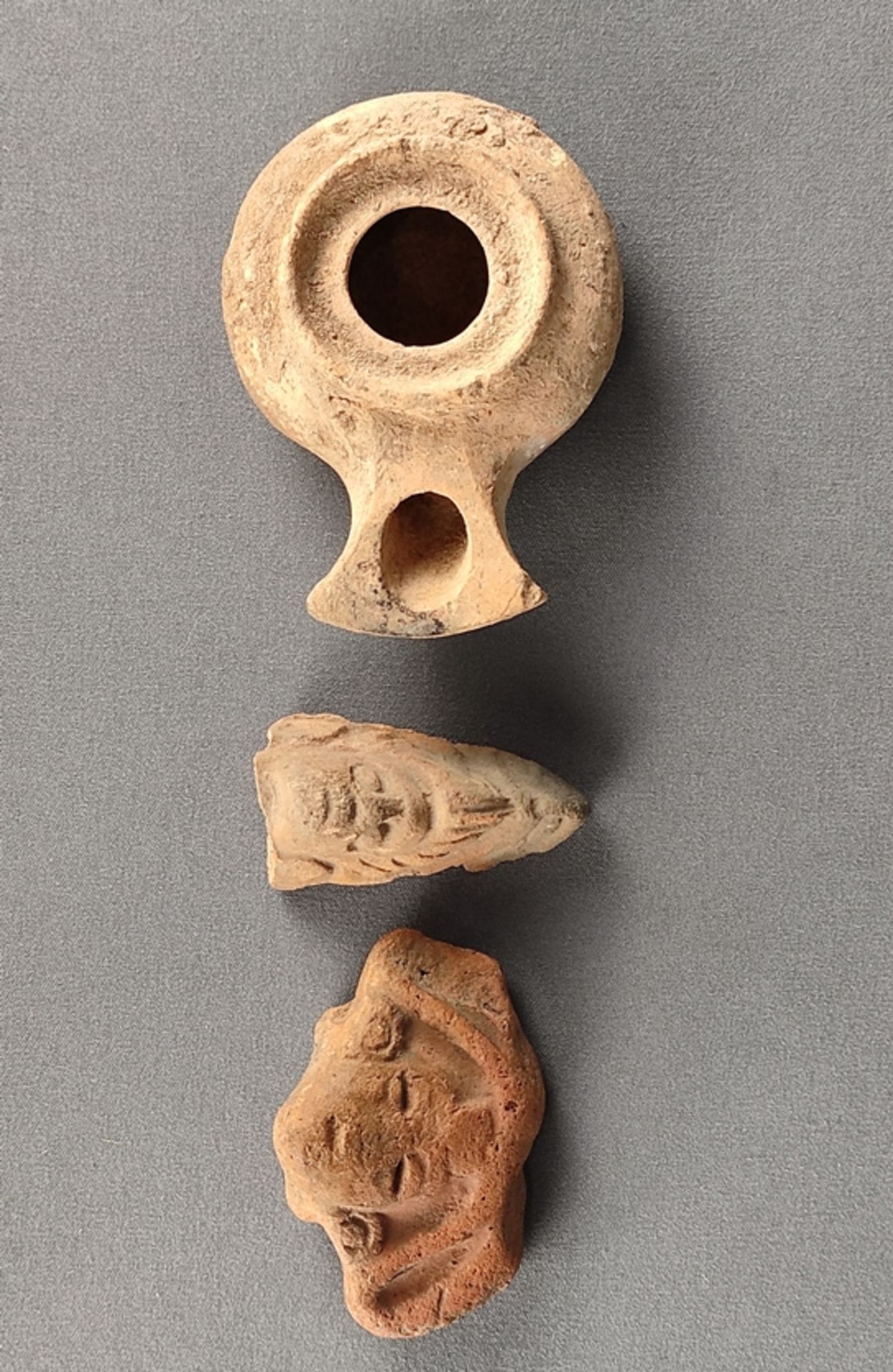 Terracotta convolute, one oil lamp, so called frog, 2,5x9x6,5 cm, and two figurine fragments, l 6cm