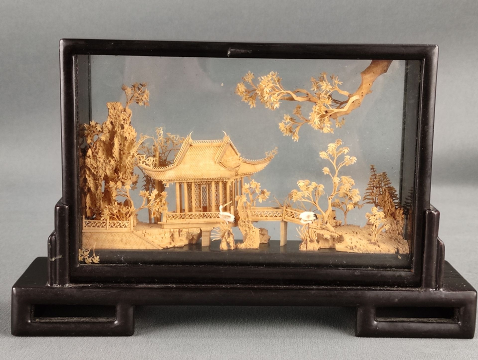 Two showcases, pagoda with cranes and trees on rocks, fine carving from cork, in semicircular showc