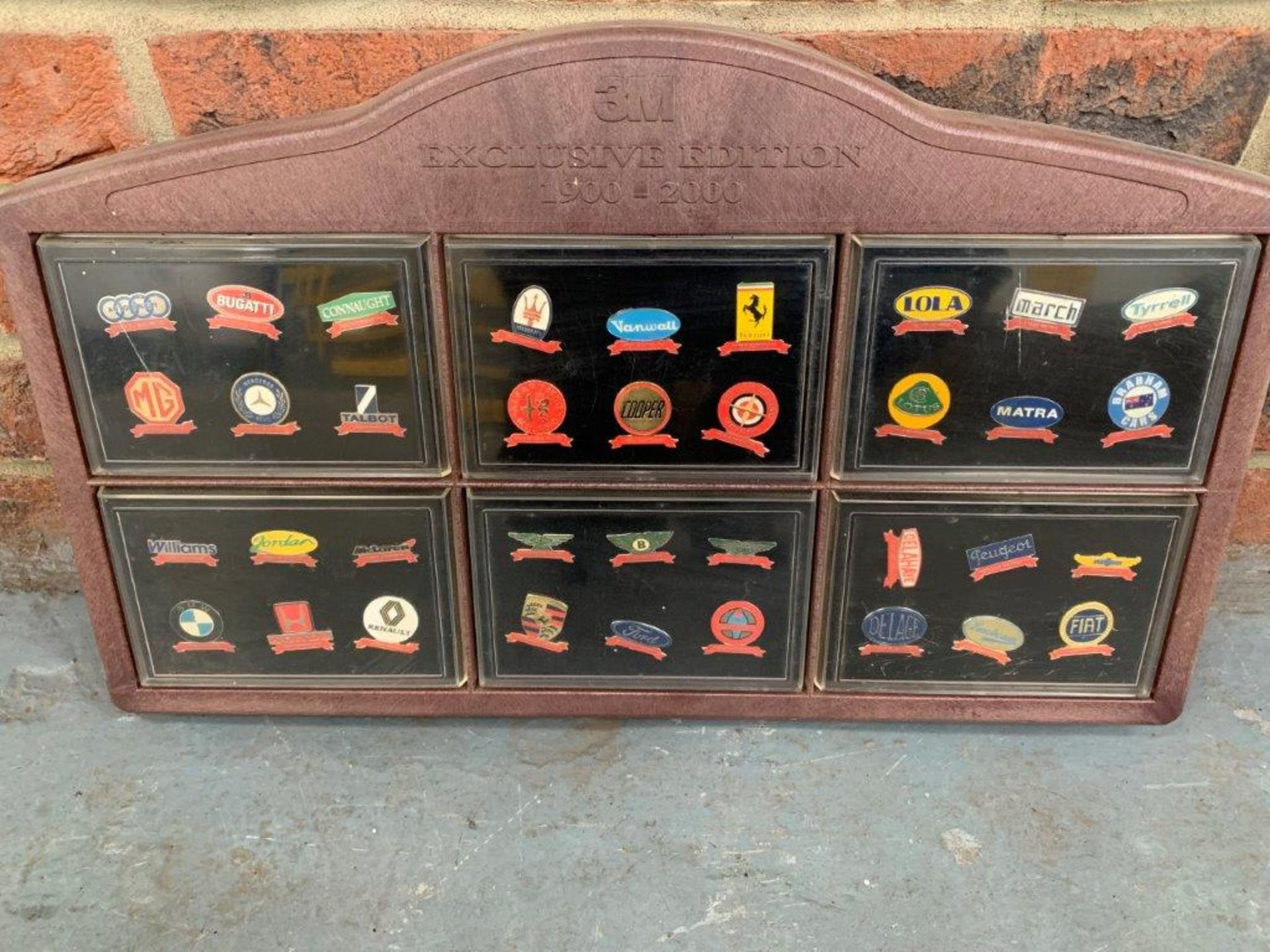 A Display Case Of 36 Car Badges