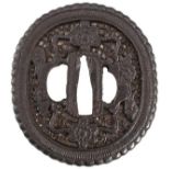 AN OVAL IRON TSUBA, chiselled and pierced with dragons, flower heads and scrolls, in wood storage