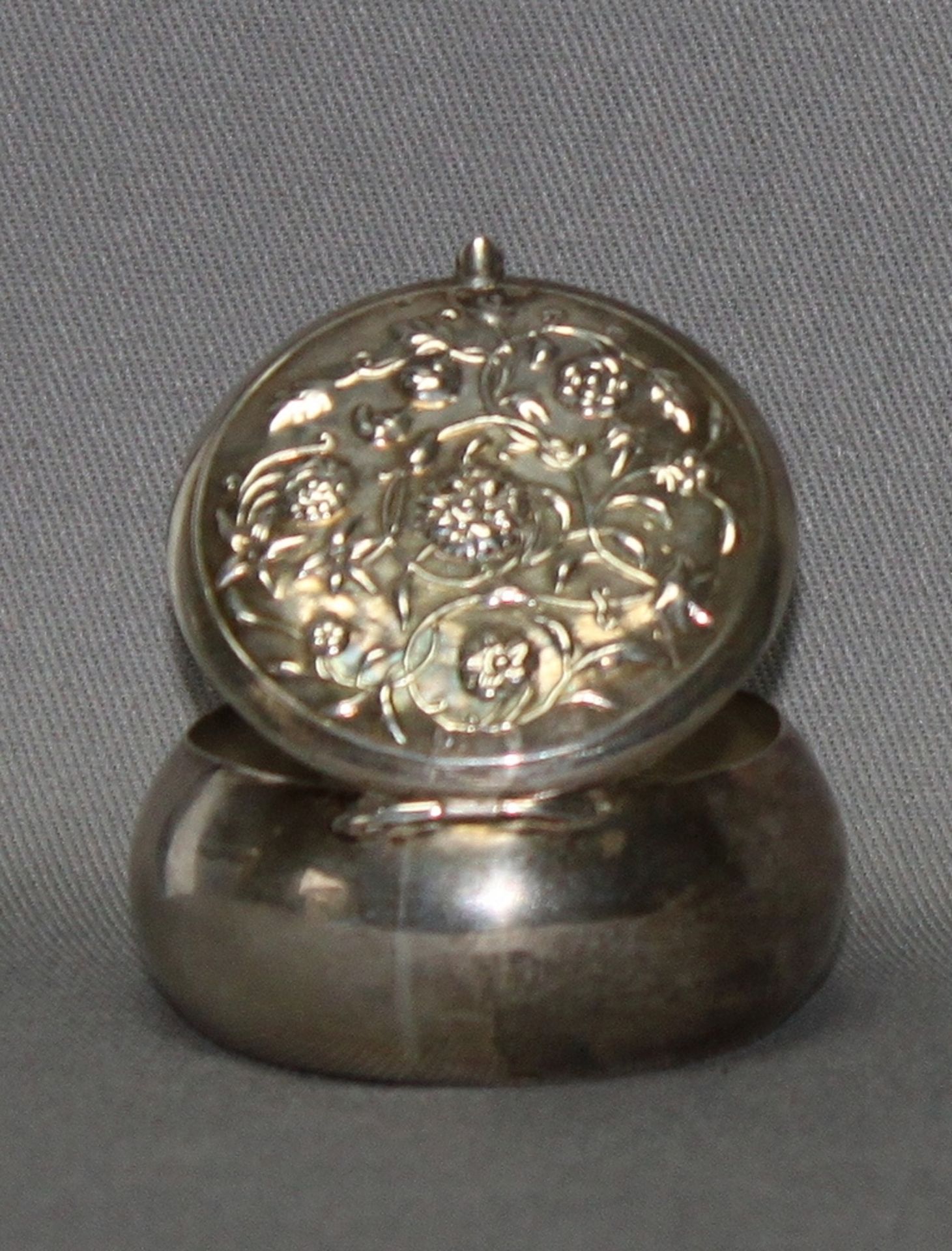 Silber. Kleine runde Pillendose mit klappbarem Deckel. Mit floralen Dekor auf dem Oberdeckel.