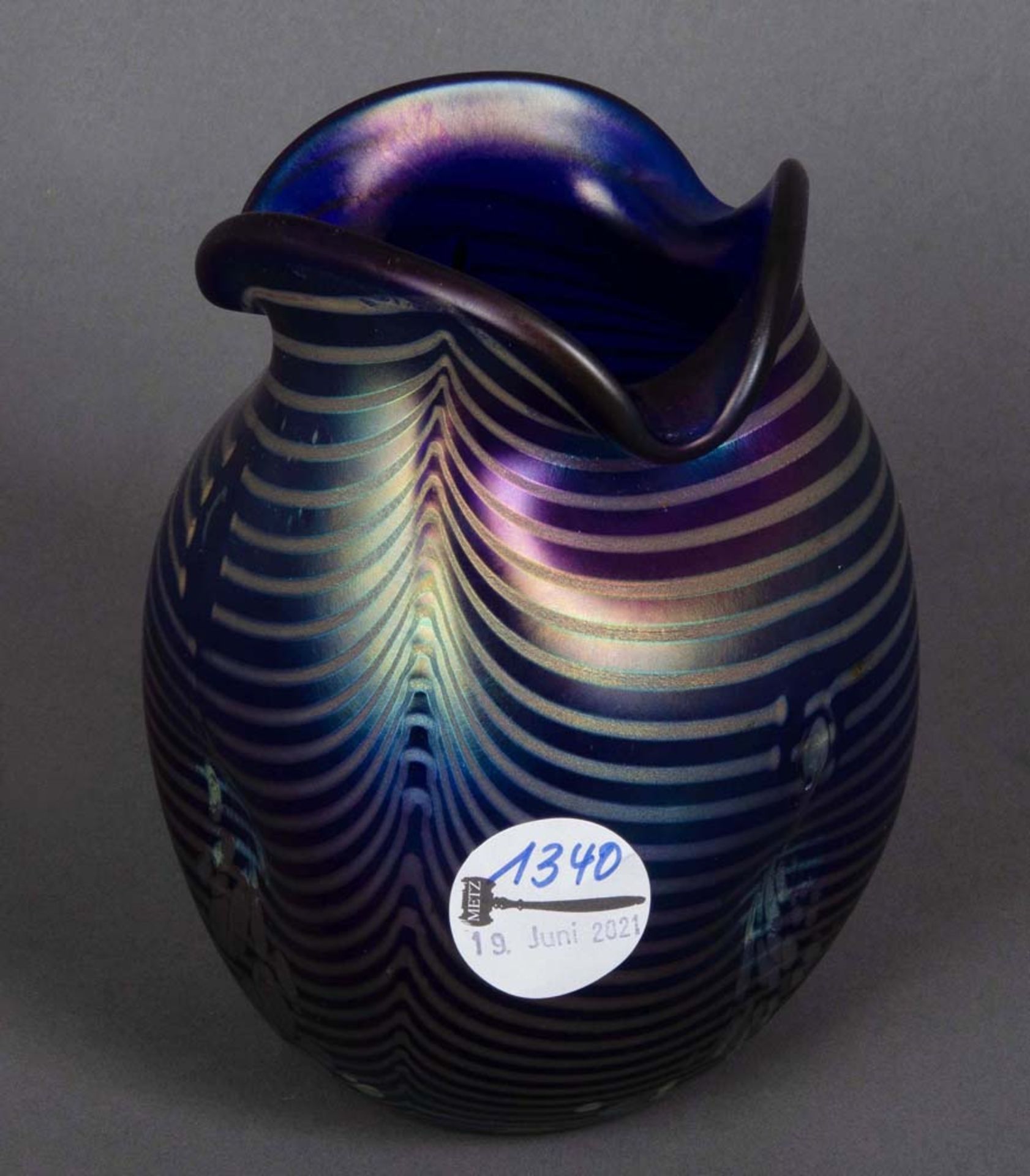 Vase. Deutsch. Farbloses Glas, violett lüstrierend überfangen mit gekämmtem Dekor, H=16 cm.